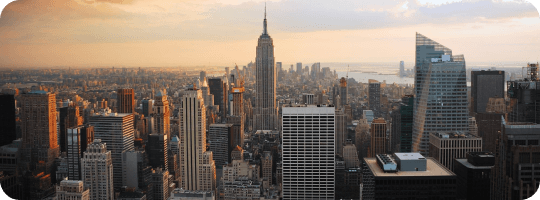 A warm sunset over Manhattan featuring the Empire State Building and surrounding skyscrapers.