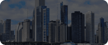 Skyscrapers of Chicago reflecting off Lake Michigan under cloudy skies.