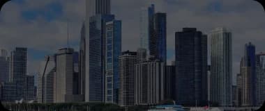 Skyscrapers of Chicago reflecting off Lake Michigan under cloudy skies.