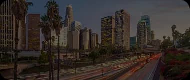 Aerial view of Los Angeles skyline with highways and palm trees at dusk