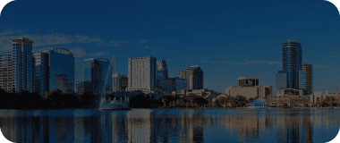 Skyscrapers reflecting on a lake in Orlando under a blue sky