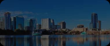 Skyscrapers reflecting on a lake in Orlando under a blue sky