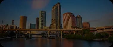 Tampa skyline with waterfront and modern buildings under a partly cloudy sky.