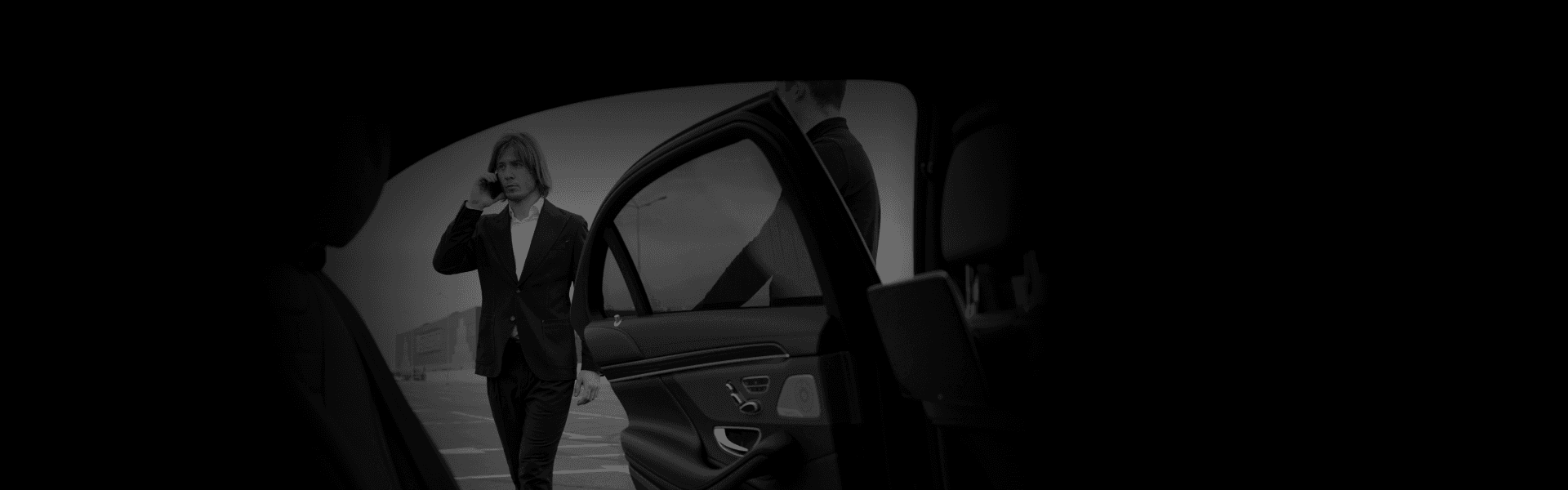 Man stepping out of a luxury vehicle during golden hour, viewed from inside the car—capturing the poised start of upscale City Tours.