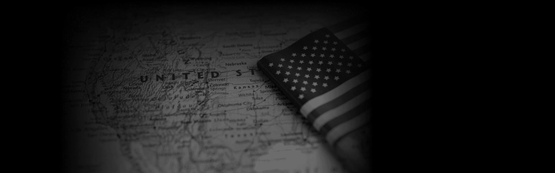 A grayscale map of the United States with a folded American flag placed over the Midwest, accompanied by the text "Premium Transportation Services Across All States" in bold white letters at the bottom.