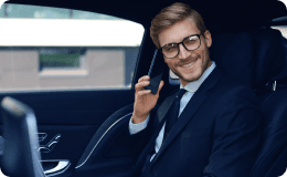 Smiling client in a suit on a call from the backseat, showcasing responsive concierge-level support experience.