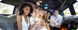 A group of friends dressed for a celebration, enjoying drinks inside a sleek limousine during an event transfer.