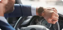 The driver is checking his wristwatch while seated behind the wheel.