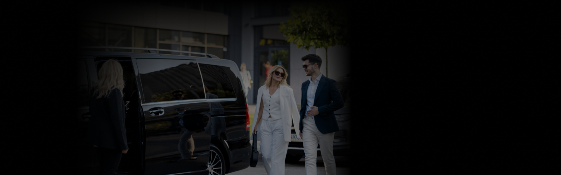 Two professionally dressed individuals walk away from a luxury black van after arrival, ideal for Meetings & Offsite Events.